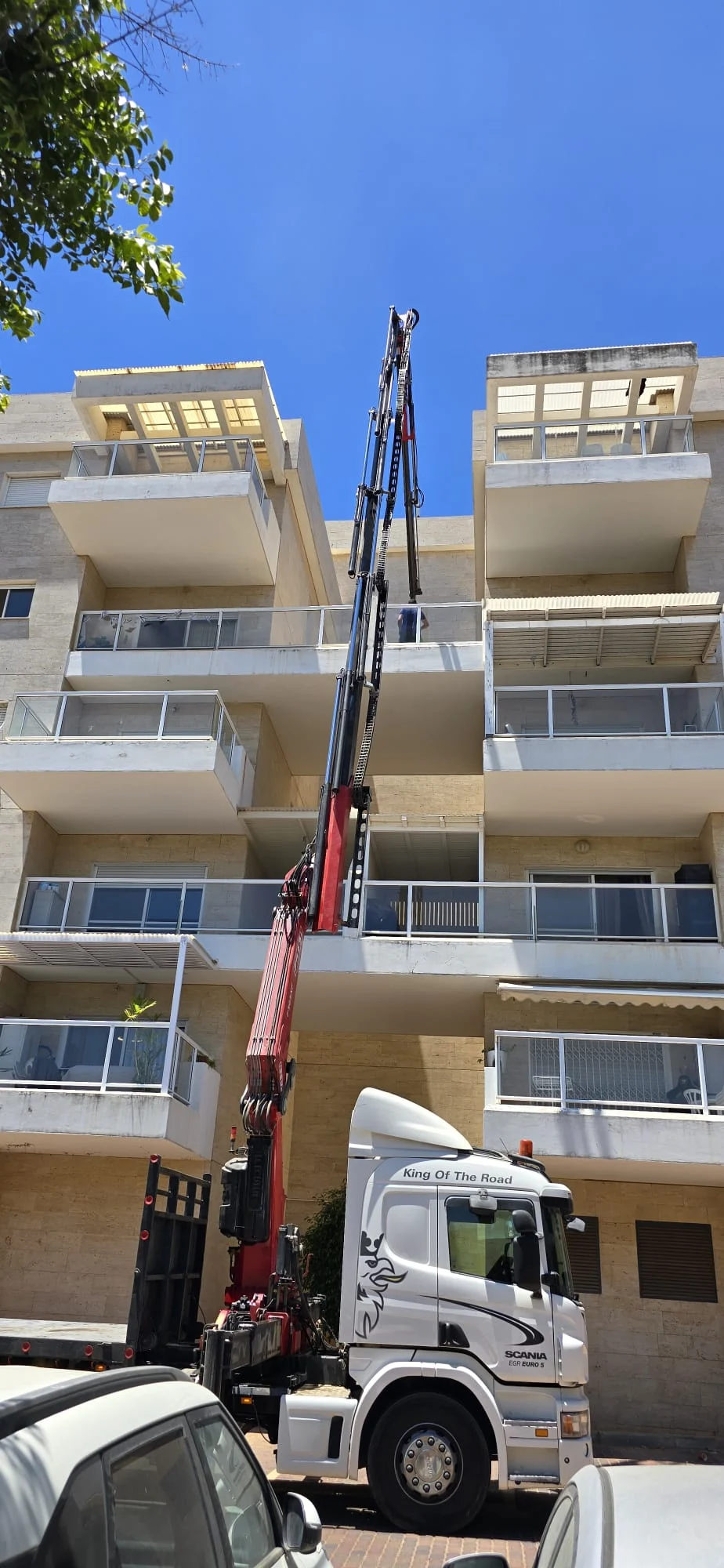 משאית מנוף עובדת לגובה לצד בניין מגורים