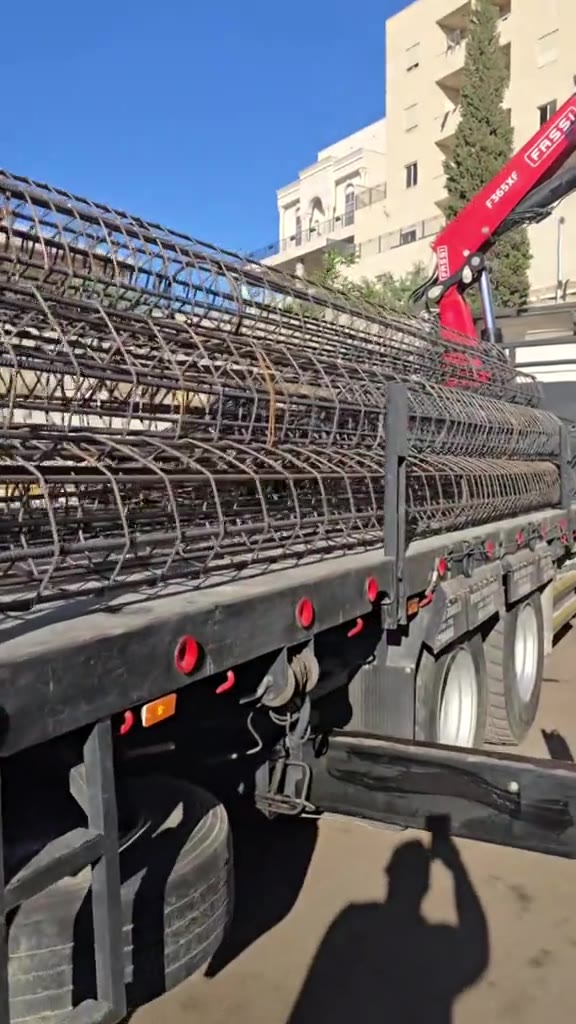 מבט על מטען הברזל, המשאית והמנוף בשטח.